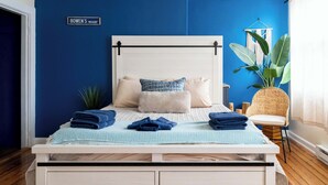 Una cama con cabecera blanca, ropa de cama azul y un letrero que dice 'BOWEN'S WHARF'.
