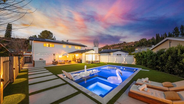 Ein modernes Haus mit Pool, Außenbereich mit Sitzgelegenheiten und einer gut beleuchteten Terrasse.