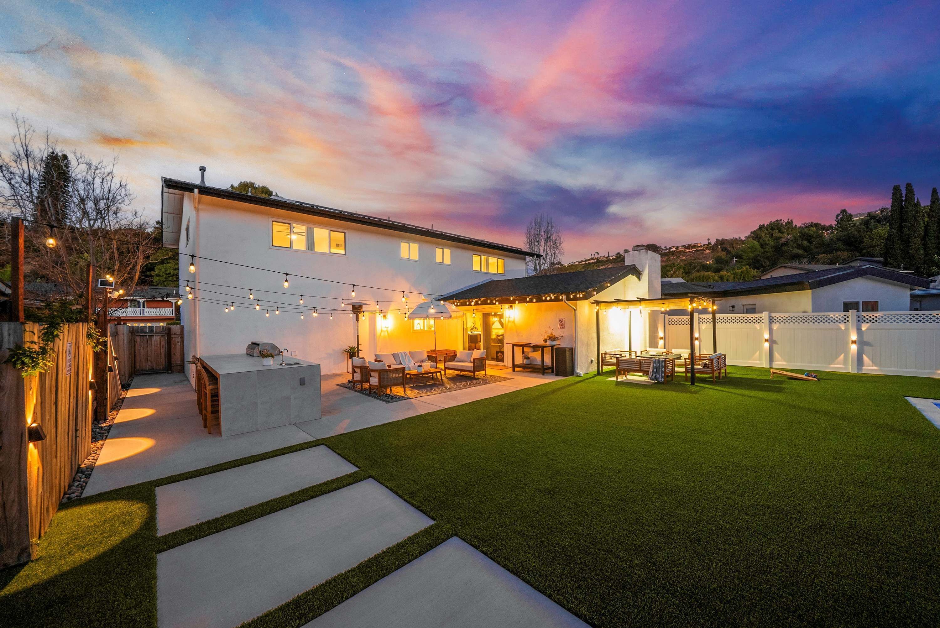 Ein modernes Haus mit gepflegtem Rasen, einer Sitzgelegenheit im Freien und Lichterketten.