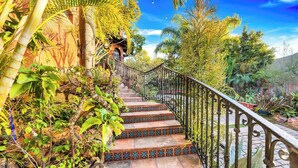 Una escalera con barandillas metálicas ornamentales y baldosas estampadas que conduce a un edificio.