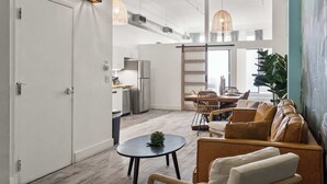 A modern living room with a sofa, a coffee table, and a dining area with chairs. - Woolworth Loft - Stay in the Heart of Gaslamp 🌆 (San Diego)