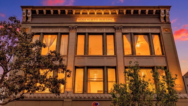 A building with the sign 'WOOLWORTH BUILDING' at the top, large windows, and a classic architectural style. - Woolworth Loft – Gaslamp 4BR Downtown Pad w/ Tub (San Diego)
