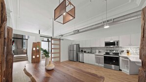 A modern kitchen with wooden flooring, stainless steel appliances, and a central island. - Woolworth Loft – Gaslamp 4BR Downtown Pad w/ Tub (San Diego)