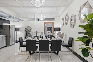 Uma sala de jantar moderna com uma mesa grande, cadeiras e espelhos decorativos.