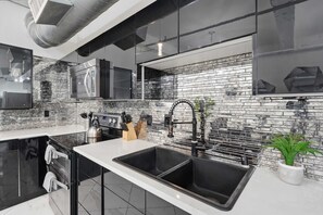 Uma cozinha moderna com uma pia dupla, eletrodomésticos de aço inoxidável e painel de parede de tijolos.