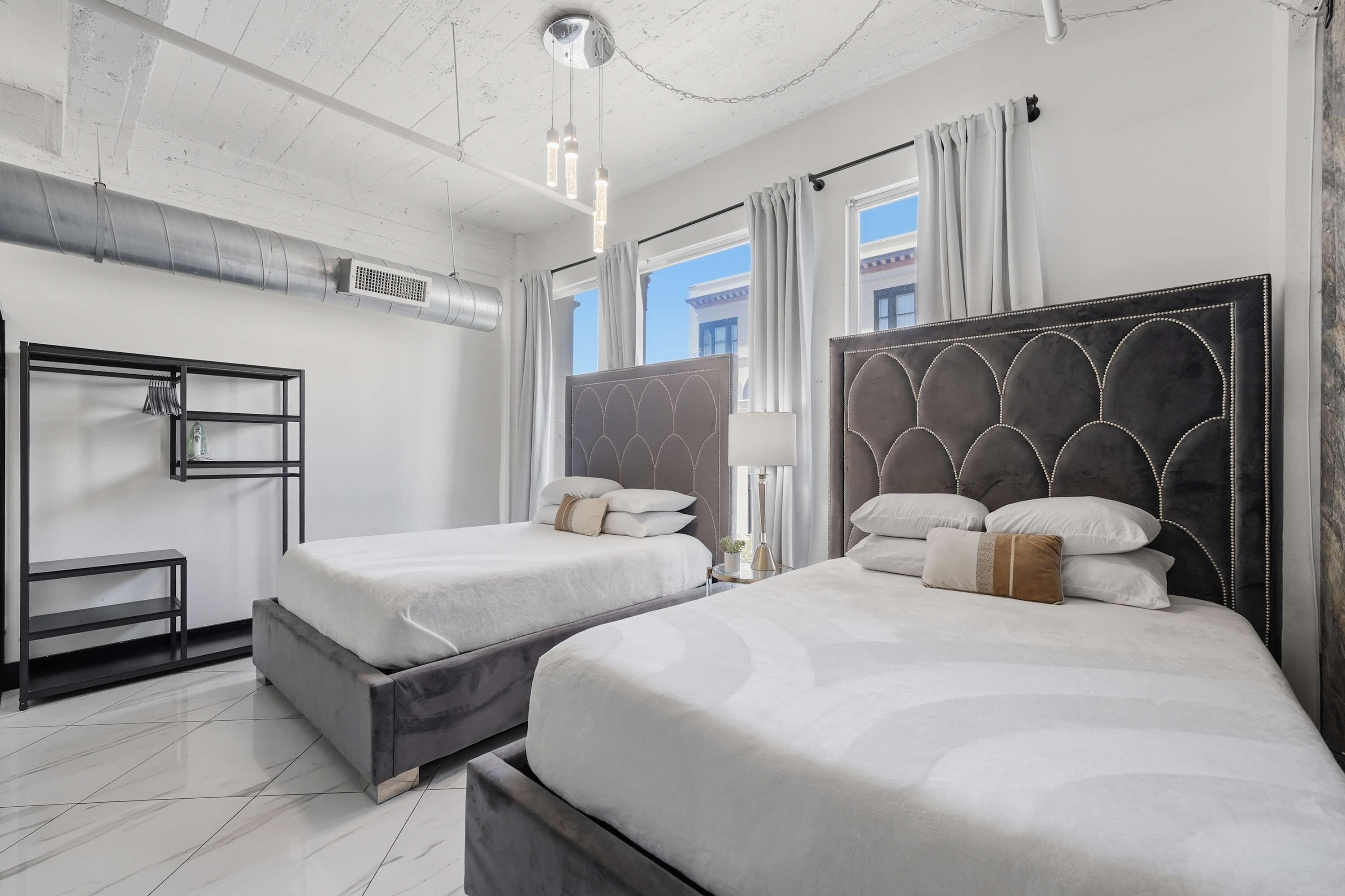 Une chambre d’hôtel avec deux lits, une armoire, un bureau et une fenêtre avec des rideaux.