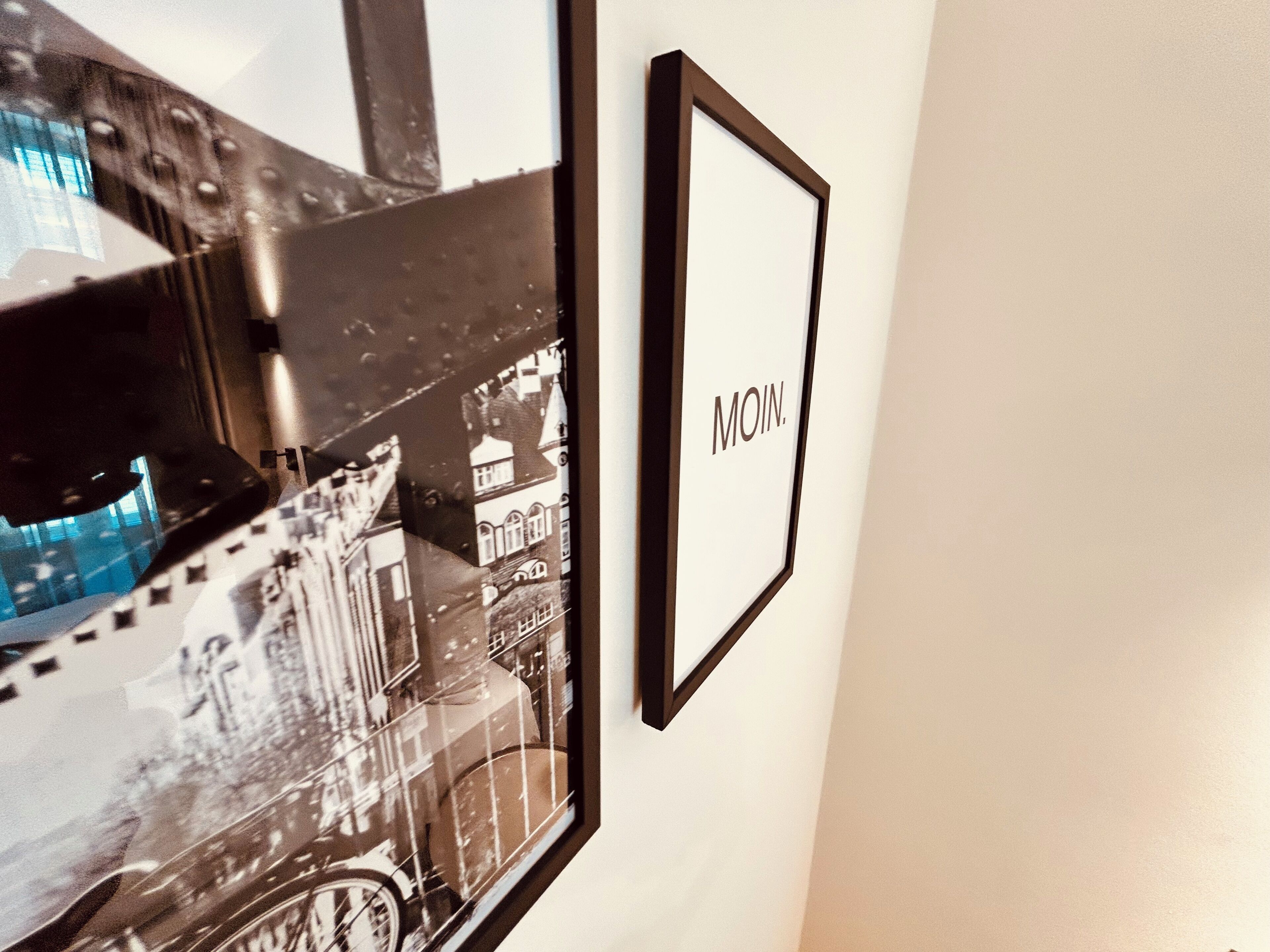 A framed photograph of a building with the word "MOIN." on it, mounted on a wall.