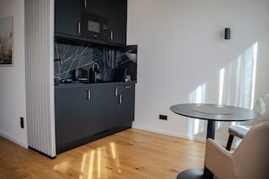 Una cocina moderna con armarios oscuros, salpicadero de mármol y una mesa redonda con una silla.