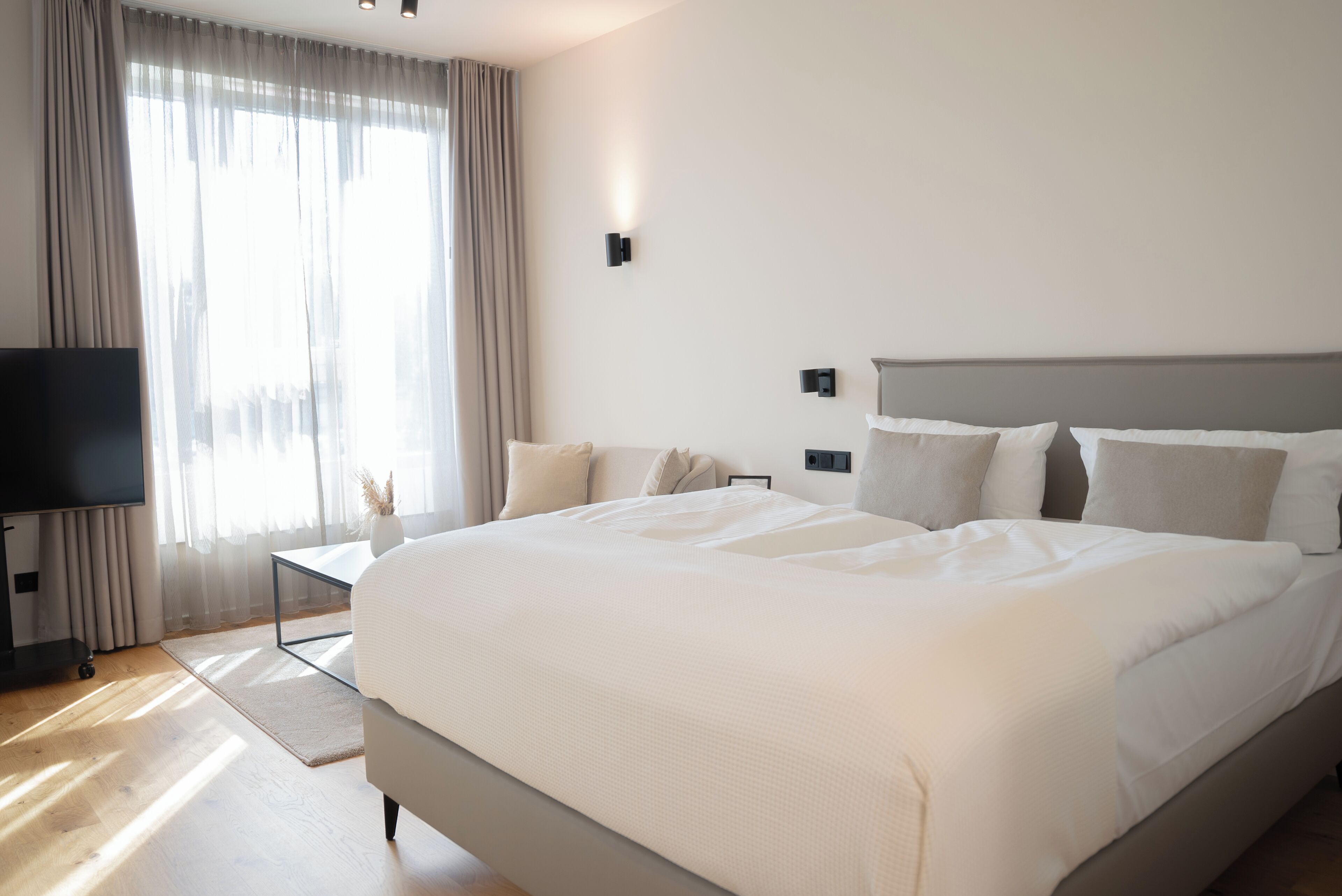 A modern hotel room with a large bed, a flat-screen TV, and a desk.