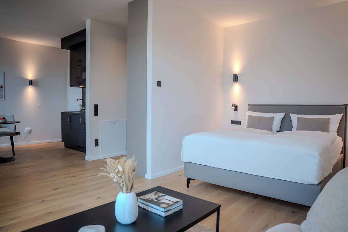 Un dormitorio moderno con una cama grande, mesitas de noche y una pequeña zona de escritorio.