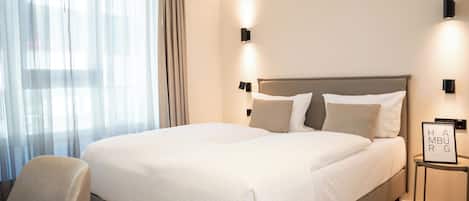 A neatly made bed with a headboard, a bedside table with a framed picture, and a chair.