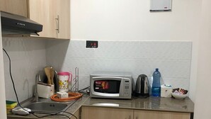 A compact kitchen with a gas stove, a microwave, a kettle, and a sink. - Kiambu Zone Heights (Nairobi)