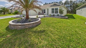 A residential house with a well-maintained lawn, a palm tree, and a driveway leading to the entrance. - Near Sawgrass Grove in The Village of Newell (The Villages)