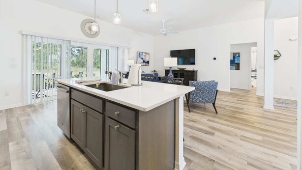 A spacious kitchen with a large island, dark cabinets, and pendant lighting. - Near Sawgrass Grove in The Village of Newell (The Villages)