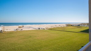 Un espace verdoyant avec une terrasse en bois et une vue sur la plage et l’océan.