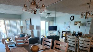 A dining area with a wooden table, woven placemats, and matching chairs. - Pier Point South Ocean View Condos B-15 (St. Augustine)