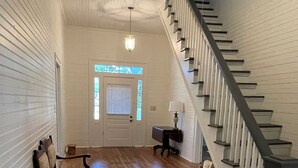 A spacious hallway with wooden flooring, a bench, a desk, and a staircase. - “Down Home” - Charming Antebellum Farm House (Edgefield)