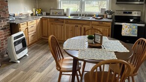 A kitchen with wooden cabinets, a dining table with chairs, a ceiling fan, and a microwave. - “Down Home” - Charming Antebellum Farm House (Edgefield)
