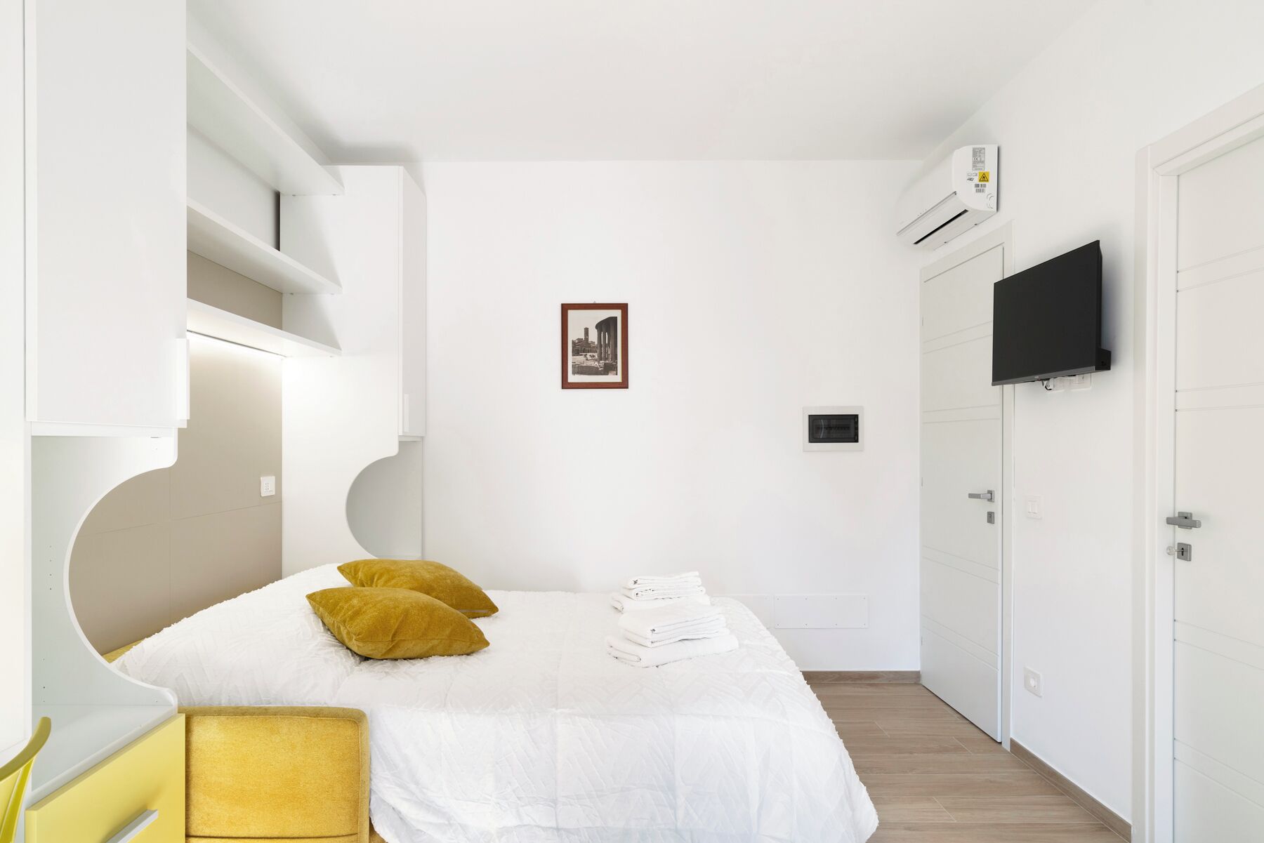 A small, modern bedroom with a bed, a TV, and a wardrobe.