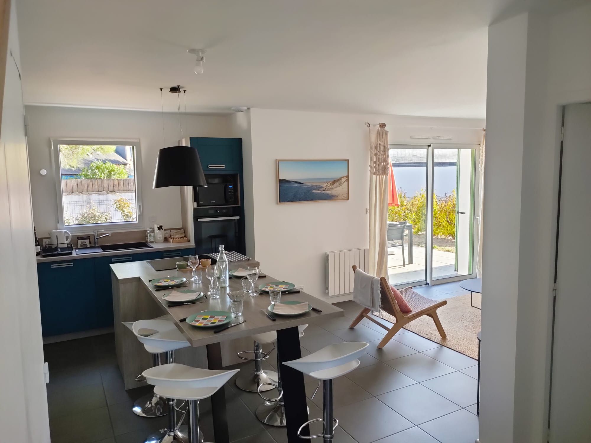 Una cocina moderna con una isla central, taburetes de bar y una mesa de comedor preparada para cuatro personas.
