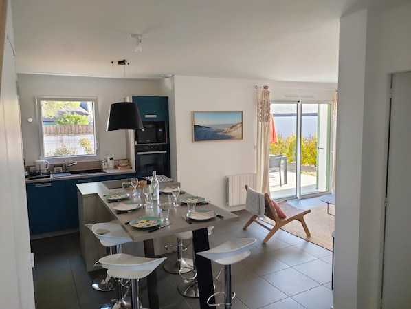 A modern kitchen with a central island, bar stools, and a dining table set for four.