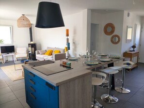 A modern kitchen with a central island, bar stools, and a dining area.