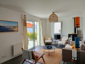 A modern living room with a large window, a television, and a sofa.