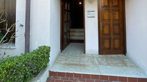 A building entrance with a wooden door, a small window, and a tiled pathway. - 3V Apartments UGO WITH POOL (Bardolino)