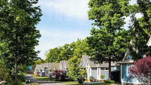 A residential street with houses, trees, and a clear sky.