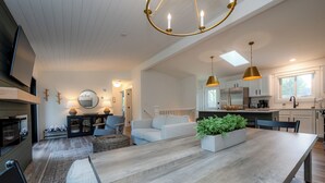 A modern kitchen with a central island, pendant lighting, and a view of the dining area. - New Buffalo With Hot Tub and Association Beach! (New Buffalo)
