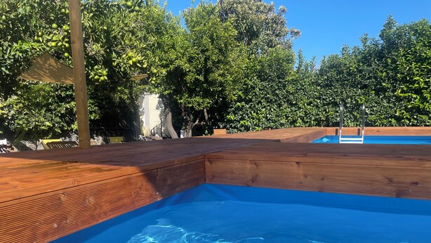 A swimming pool with wooden deck edges and a clear blue water surface. - Superior Apartment to Pompeii (Boscoreale)