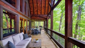 A covered porch with a sofa, dining table, and chairs.