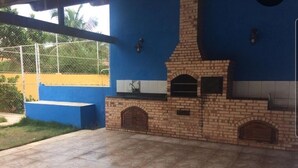 An outdoor patio with a brick barbecue area, a blue wall, and a tiled floor. - Holiday home in Araruama/ Praia Seca. Located in the Palm Beach condominium (Praia Seca)
