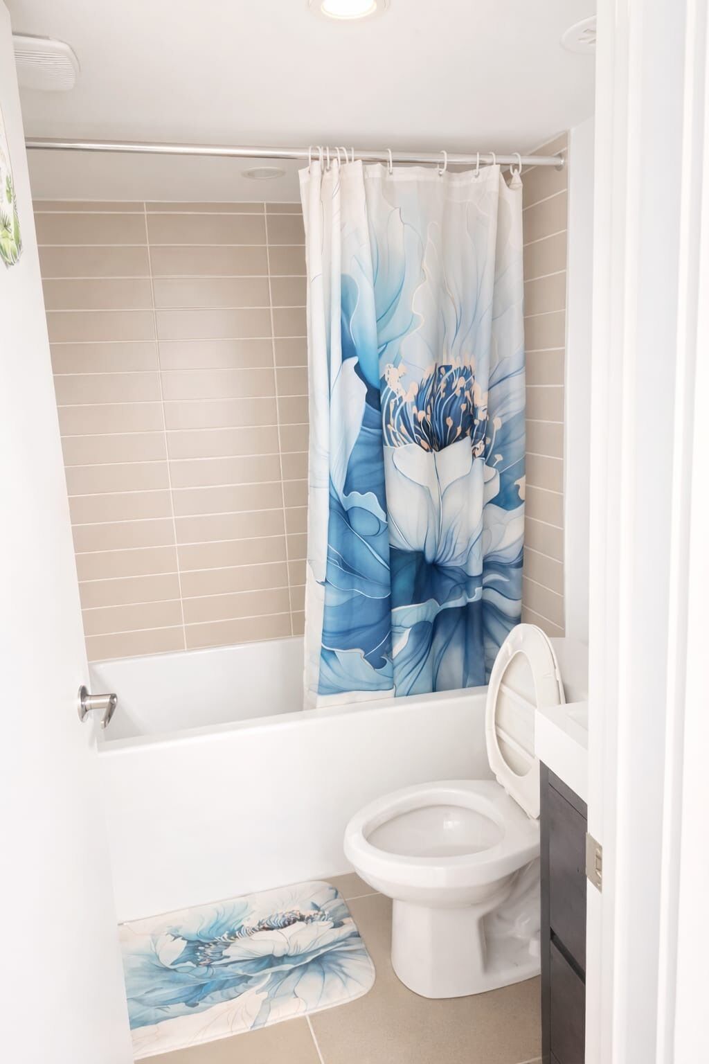 A bathroom with a bathtub, toilet, and a shower curtain with a floral design.
