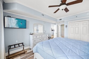 A bedroom with a bed, dresser, mirror, and a ceiling fan.