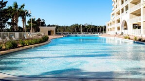 Ein großer, sauberer Pool mit Liegestühlen und ein Gebäude mit mehreren Balkonen im Hintergrund.