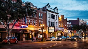 A street lined with multi-story buildings, some with commercial establishments on the ground floor. - Eminence Sleek Studio City View (Edmonton)