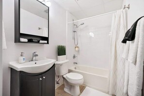 Une salle de bain moderne avec un lavabo, des toilettes et une baignoire, le tout de couleur blanche.
