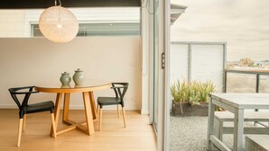 Un espace repas moderne avec une table ronde en bois, deux chaises noires et un luminaire suspendu.