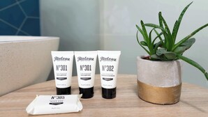 Trois flacons de produits de soins capillaires de la marque Biolage et une plante d’aloe vera en pot, le tout posé sur une surface en bois.