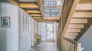 Ein Korridor mit einer Holztreppe, weißen Türen und einem gefliesten Boden.
