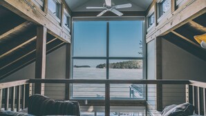 Ein Zimmer mit großem Fenster, Deckenventilator und Blick auf ein Gewässer.