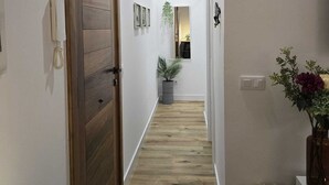 Ein Flur mit einer Holztür, einem Blumentopf und einer Vase mit Blumen.