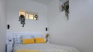 Ein Schlafzimmer mit einem Bett, einem Nachttisch, einem Fenster und einer Wanduhr.