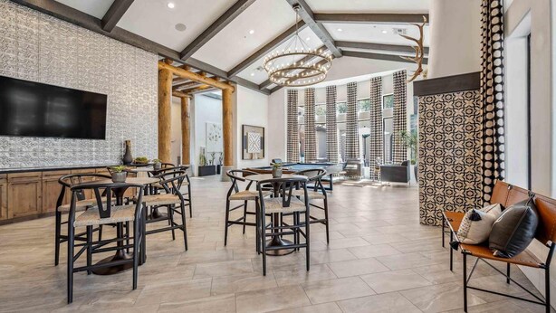 A spacious living area with a pool table, bar seating, and a large TV.