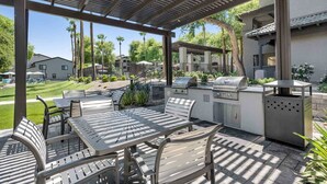 An outdoor patio with a grill, seating area, and a view of the neighborhood.