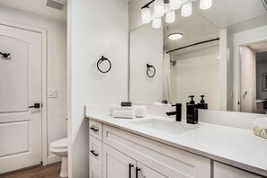 A modern bathroom with a white sink, black soap dispensers, and a large mirror. - Boulevard Stays Quiet Modern 1BR Pickleball, Pool, Parking, Gym 07 (Chandler)