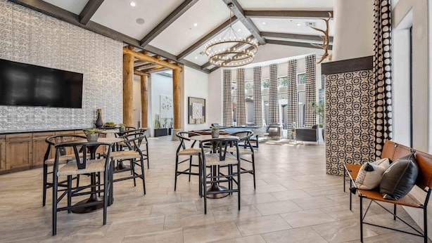 A spacious living area with a pool table, bar seating, and a large TV.
