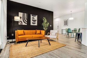 Un salon moderne comprenant un canapé, une table basse et un coin repas avec des chaises.