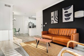 A modern living room with a leather sofa, a coffee table, and abstract wall art.